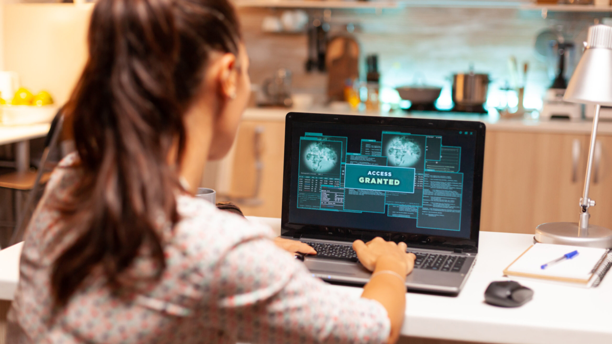 Hacker woman launching a cyberattack on bank firewall from home during night time. Programmer writing a dangerous malware for cyber attacks using performance laptop during midnight.